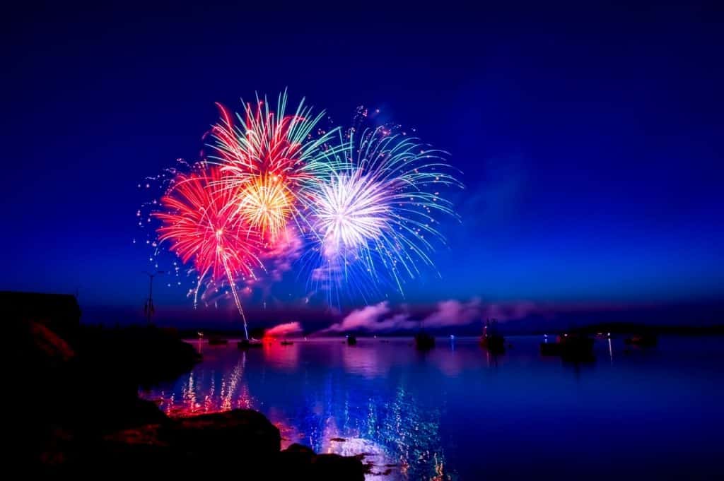 A colorful fireworks display over a body of water.