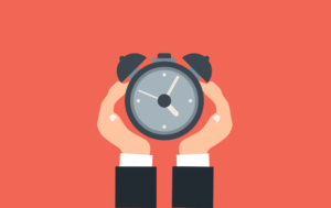 A hand holding an alarm clock on a red background.